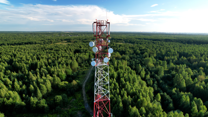 Anténa mobilnej siete stojí uprostred zelenej krajiny. Vizualizácia pokrytia 5G sieťou Telekomu pre 96,7 % populácie Slovenska.