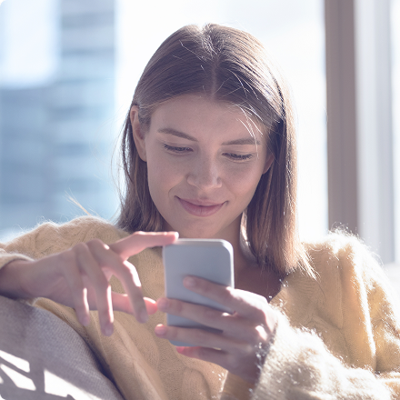 Mladá žena drží smartfón a usmieva sa, služba cieleného SMS marketingu.