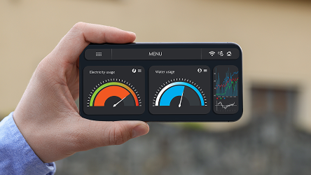 Ruka drží mobil so zobrazením meradiel spotreby vody a elektriny. Predstavuje presný odpočet spotreby pomocou Smart Meteringu.