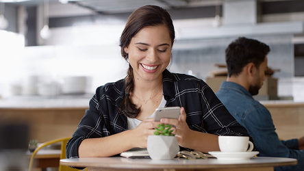Zákazníčka v kaviarni pracuje so smartfónom pri stole – vizuál služby Market Locator od Telekomu.