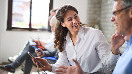 Kolegyňa sa smeje počas tímovej diskusie – symbolizuje spokojný tím a efektívnu správu firemných zariadení.