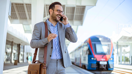Biznis muž telefonuje na vlakovej stanici – znázorňuje spoľahlivý signál aj v odľahlých oblastiach vďaka firemným riešeniam.