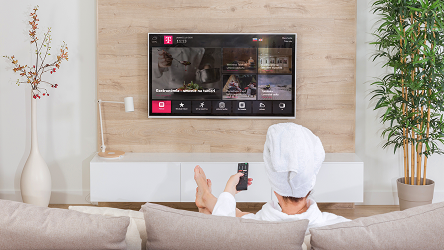 Hotelový hosť sleduje televíziu z postele – demonštruje využitie TV ako súčasť zákazníckej skúsenosti v hoteli.