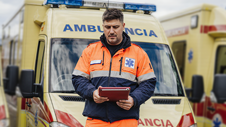 Zdravotník s tabletom pred sanitkou – prehľad o jazdách a reportovanie pohybu zdravotníckych vozidiel pre kontrolné orgány.