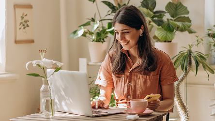 Mladá žena pracuje s úsmevom na diaľku z domu cez laptop – znázorňuje flexibilitu cloudového riešenia pre online biznis.