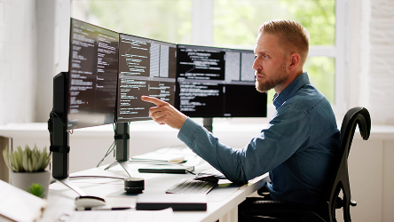 IT špecialista pracuje na viacerých monitoroch v technologickom prostredí – zdôrazňuje spoľahlivú konektivitu a zabezpečenie siete.