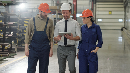 Logistický tím diskutuje pri tablete v sklade s vysokými regálmi.