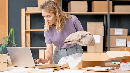 Pracovníčka e-shopu pripravujúca balík pri počítači – vizuál služby Telekom SMS & RCS Messaging.