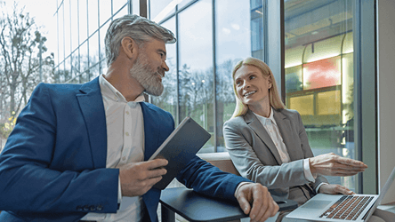 Členovia vedenia firmy diskutujú nad pracovnými podkladmi pri stole v modernom kancelárskom prostredí – vizuál služby T-Biznis Flex od Telekomu.